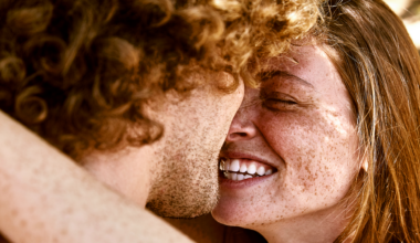 two redheaded people - a man and a woman - hugging and looking at one another