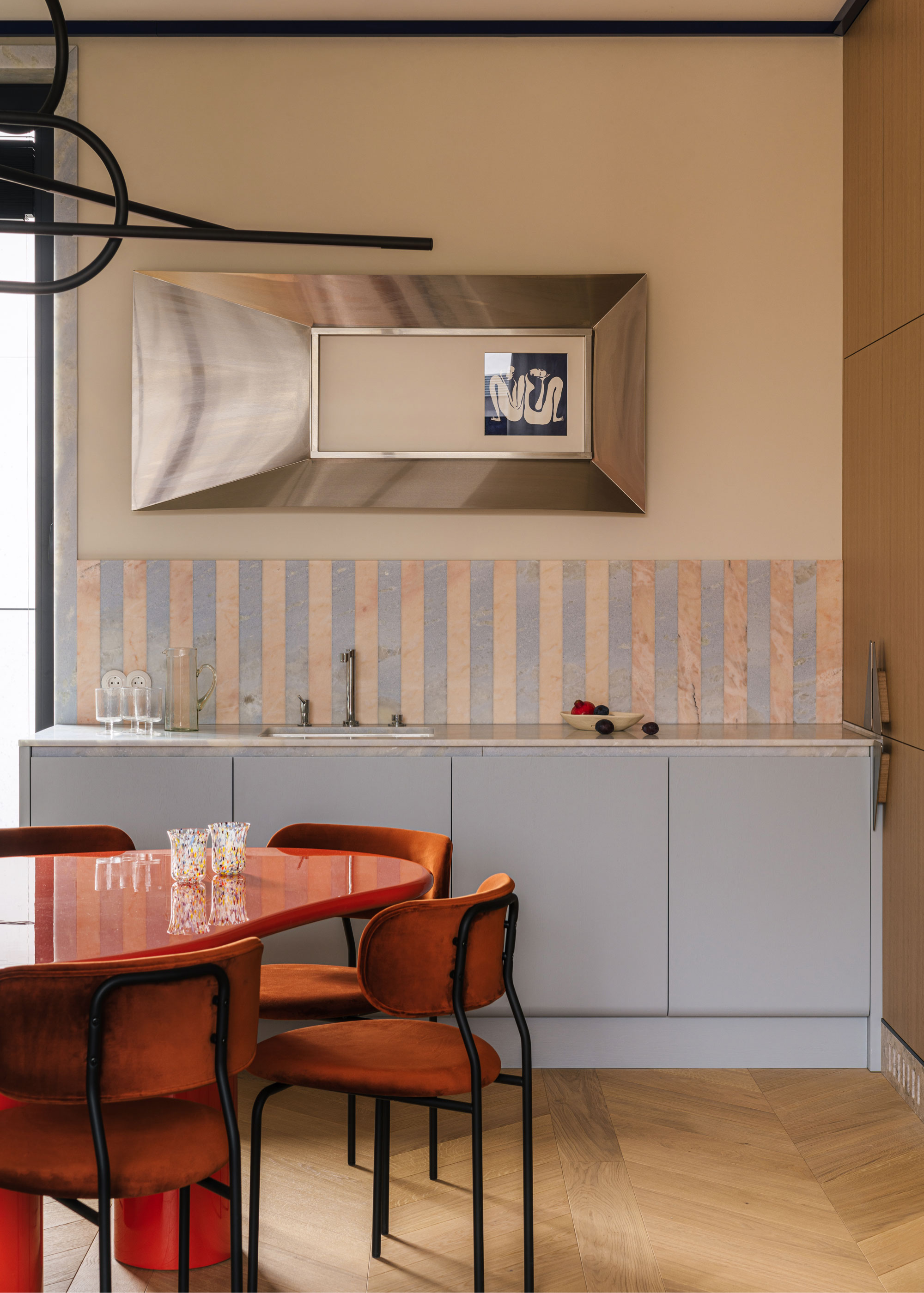 a light blue kitchen with red table and chairs in front of it. A striped backsplash tle is on the wall