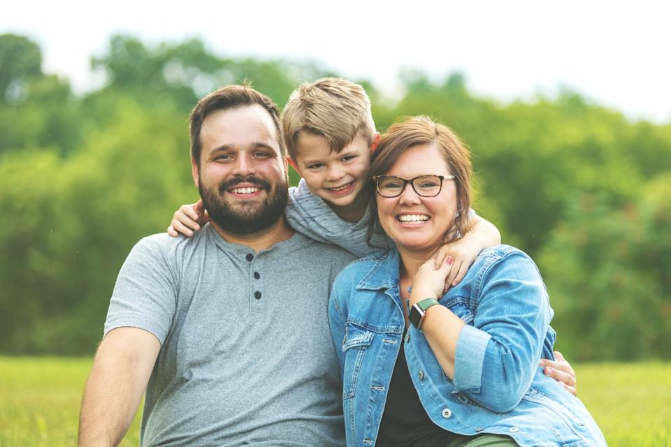 A family is outdoors, smiling.