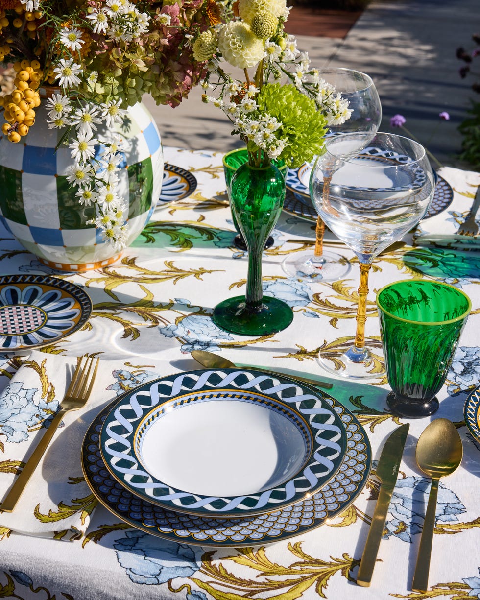 Dining table set with decorative plates, glassware, and flowers