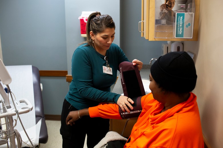 A medical professional takes a blood pressure reading from a seated patient