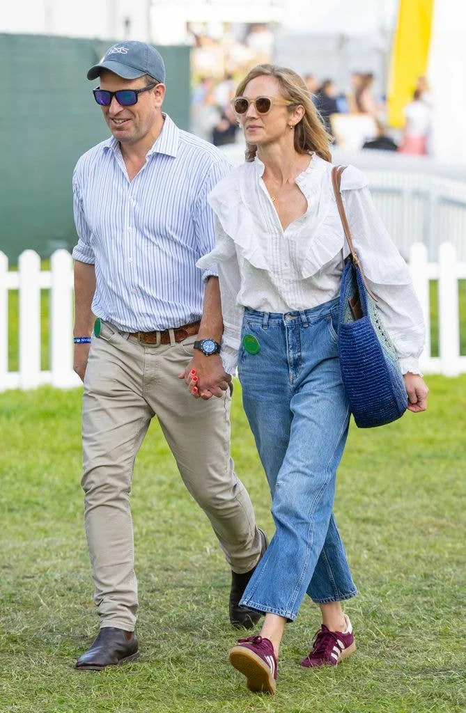 Peter Phillips and Harriet Sperling walk hand in hand in field