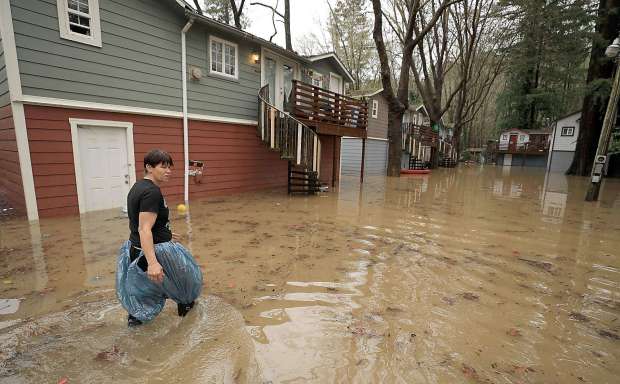 Sycamore Court resident Chris Tipton looks for floating toys and personal belongings of the park's residents flooded by Armstrong Creek, Thursday, Feb. 14, 2019 in Guerneville. Sycamore Court flooding is one of the first indicators that the Russian River is backing up tributaries that feed in to the river. (Kent Porter / The Press Democrat) 2019