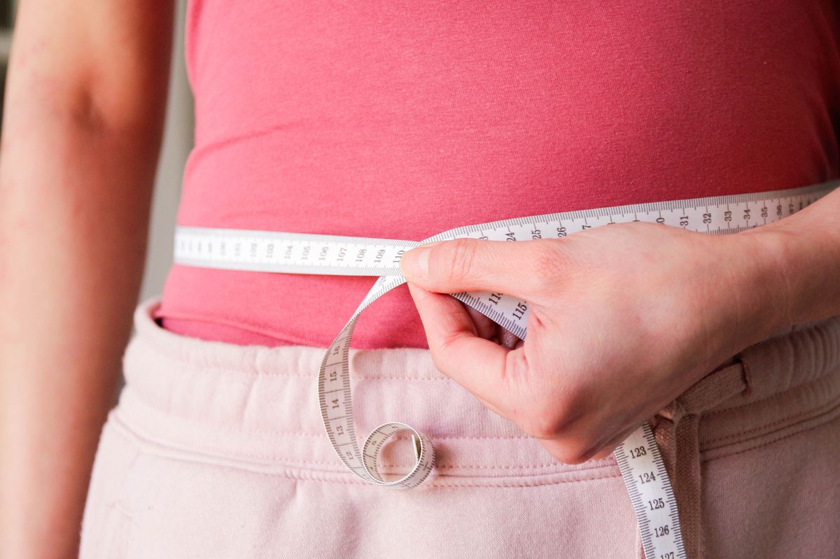 Woman using a measuring tape on her waist