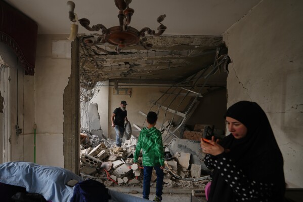 Fadi Al Zein, left, who lost both his homes in Israeli strikes in his village of Khiam and in Dahiyeh, searches through the rubble of his heavily damaged home as a child stands nearby, in Beirut's southern suburbs, Lebanon, Saturday, April 25, 2026. (AP Photo/Hassan Ammar, File)