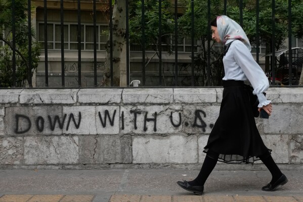 A woman walks past an anti-U.S. graffiti painted on the wall of the Tehran University on Enqelab-e-Eslami (Islamic Revolution) street in downtown Tehran, Iran, Saturday, April 25, 2026. (AP Photo/Vahid Salemi, File)