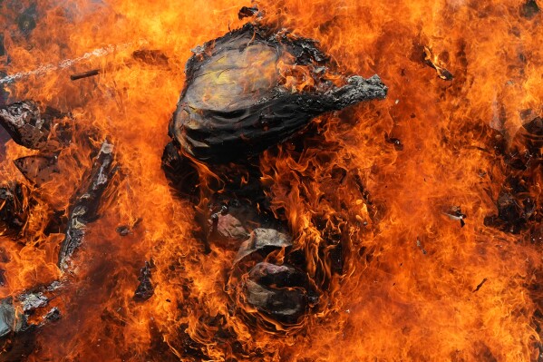 Protesters burn an effigy of U.S. President Donald Trump during a May Day rally in Manila, Philippines on Friday, May 1, 2026. (AP Photo/Aaron Favila)