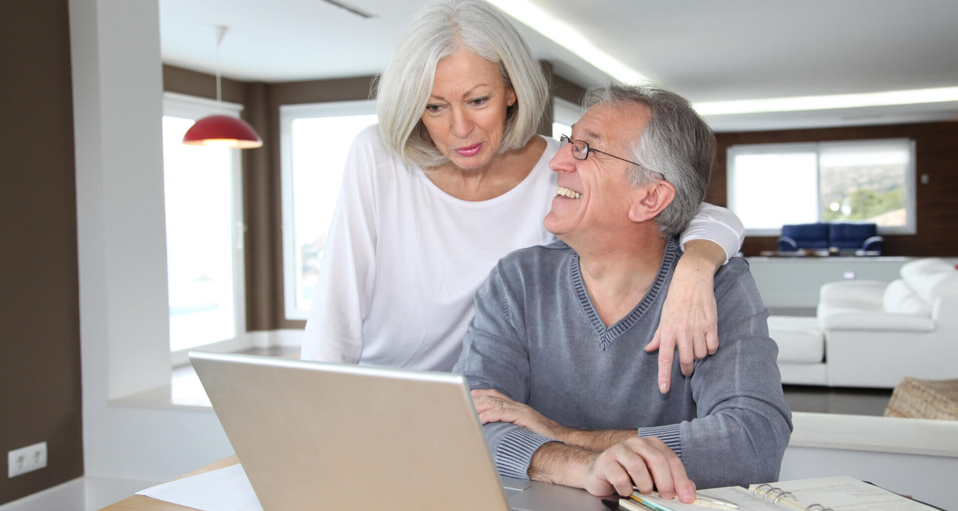 Senior couple using laptop and celebrating a win with their finances, retirement planning, Social Security and more.