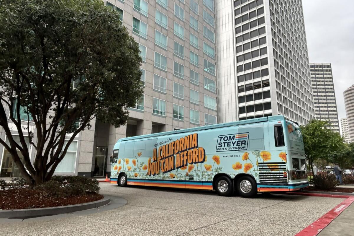 A bus with the message "All Aboard For A California You Can Afford" and "Tom Steyer for Governor" on its side is parked.