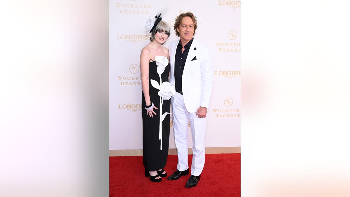 Dannielynn Birkhead and Larry Birkhead standing at Churchill Downs during the Kentucky Derby.