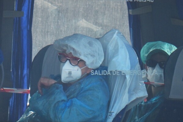 Passengers sit inside a bus after being disembarked from the hantavirus-stricken cruise ship MV Hondius at the port of Granadilla in Tenerife, Canary Islands, Spain, Sunday, May 10, 2026. (AP Photo/Manu Fernandez)