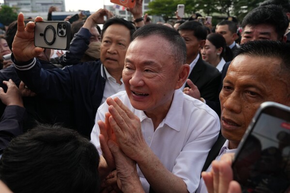 Former Thailand Prime Minister Thaksin Shinawatra, center, gestures to his supporters following his release on parole from a Bangkok prison in Bangkok, Thailand, Monday, May 11, 2026. (AP Photo/Sakchai Lalit)