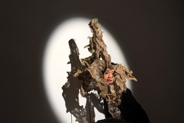 Gallery assistant Katelyn Liu looks towards The Scholar's Rock textile sculpture - textile by Elaine Yang Ling Ng, Guangzhou embroidery by Wang Xinyuan, during a media unveiling at the Royal Society of Sculptors as London Craft Week welcomes visitors to a citywide celebration of craftsmanship and creativity from around the world, in London, Monday, May 11, 2026. (AP Photo/Kirsty Wigglesworth)