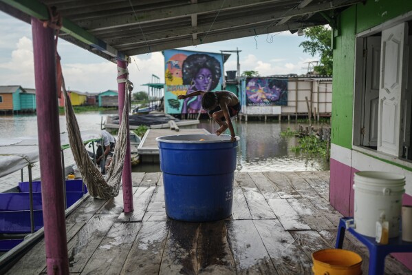 A child jumps into a container of water Thursday, April 30, 2026, in Nueva Venecia, Colombia. (AP Photo/Ivan Valencia)