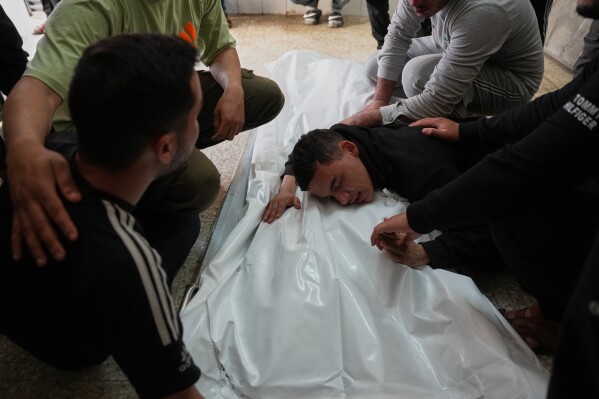 Palestinian Muath Al-Shaafi center cries over the body of his brother Abdulrahman Al-Shaafi, who was killed in an Israeli airstrike, during his funeral at Al-Aqsa Hospital in Deir al-Balah, central Gaza Strip, Tuesday, May 12, 2026. (AP Photo/Abdel Kareem Hana)