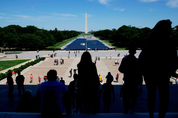 Tourists visit the Lincoln Memorial as workers apply a blue protective coating to the Lincoln Memorial Reflecting Pool, Tuesday, May 12, 2026, in Washington. (AP Photo/Rahmat Gul)