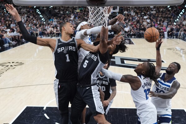 San Antonio Spurs forward Victor Wembanyama (1) and guard Stephon Castle (5) battle Minnesota Timberwolves forward Jaden McDaniels, center, for a rebound during the first half of Game 5 of an NBA basketball second-round playoffs series in Minneapolis, Tuesday, May 12, 2026. (AP Photo/Eric Gay)