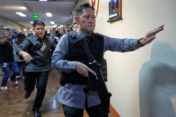 Senate security run after gunfire was heard along a hallway at the Philippine Senate in Pasay, Philippines, Wednesday, May 13, 2026. (AP Photo/Aaron Favila)
