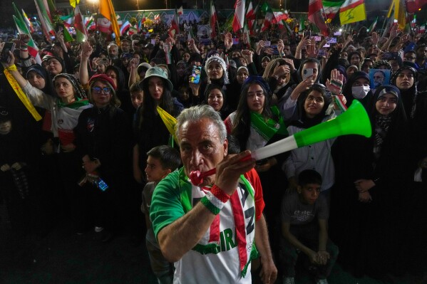 A man wearing a shirt bearing Iran's national soccer team logo blows a plastic trumpet during a pro-government gathering in support of Iran's World Cup team at Islamic Revolution Square in Tehran, Iran, Wednesday, May 13, 2026. (AP Photo/Vahid Salemi)