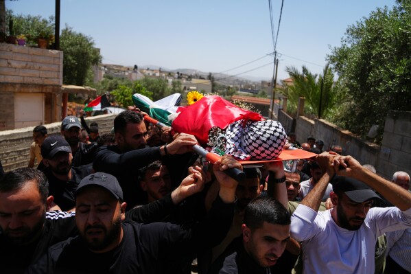 Mourners carry the body of Palestinian Zakaria Qatousa during his funeral in the West Bank town of Deir Qaddis, Wednesday, May 13, 2026. (AP Photo/Mahmoud Illean)