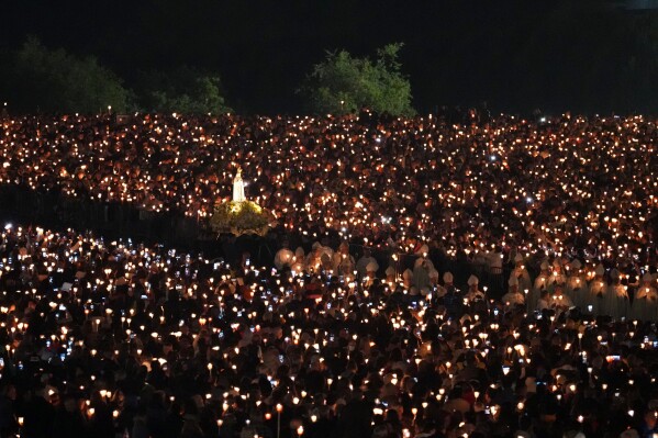 The statue of Our Lady of Fatima is carried through the crowd during the Procession of Candles, the highlight of celebrations at the Catholic shrine in Fatima, Portugal, Tuesday, May 12, 2026. (AP Photo/Armando Franca)