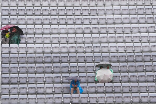 Spectators shelter with umbrellas as the quarter-final match between Karen Khachanov, of Russia, and Casper Ruud, of Norway, is suspended due to rain at the Italian Open tennis tournament in Rome, Wednesday, May 13, 2026. (AP Photo/Gregorio Borgia)