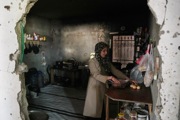 Palestinian graphic designer Reem Alkhateeb, 33, stands in her kitchen, which was damaged by Israeli air and ground operations in Khan Younis, southern Gaza Strip, March 9, 2026. (AP Photo/Abdel Kareem Hana)