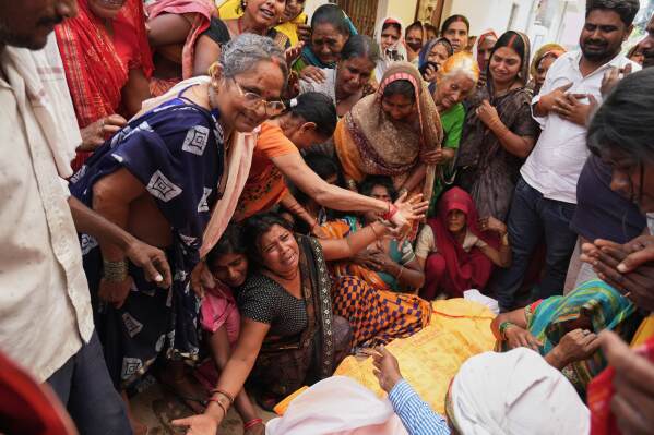 Relatives mourn beside the body of Summit Yadav, 24, who died after the wall of his neighbor's house collapsed following dust storms and heavy rain in Prayagraj, India, Thursday, May 14, 2026. (AP Photo/Rajesh Kumar Singh) CORRECTION: Corrected to that Yadav died after the wall of his neighbor's house collapsed, not his own house's.