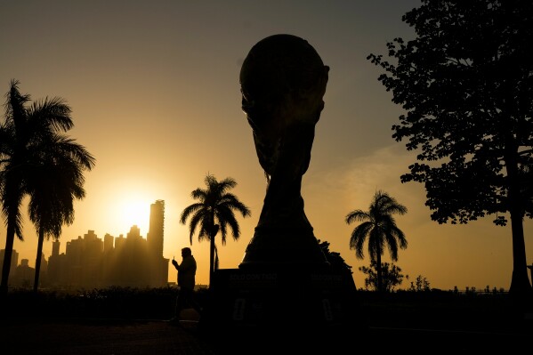A man walks next to a replica of the FIFA World Cup trophy during sunrise at the Cinta Costera in Panama City, Thursday, May 14, 2026. (AP Photo/Matias Delacroix)