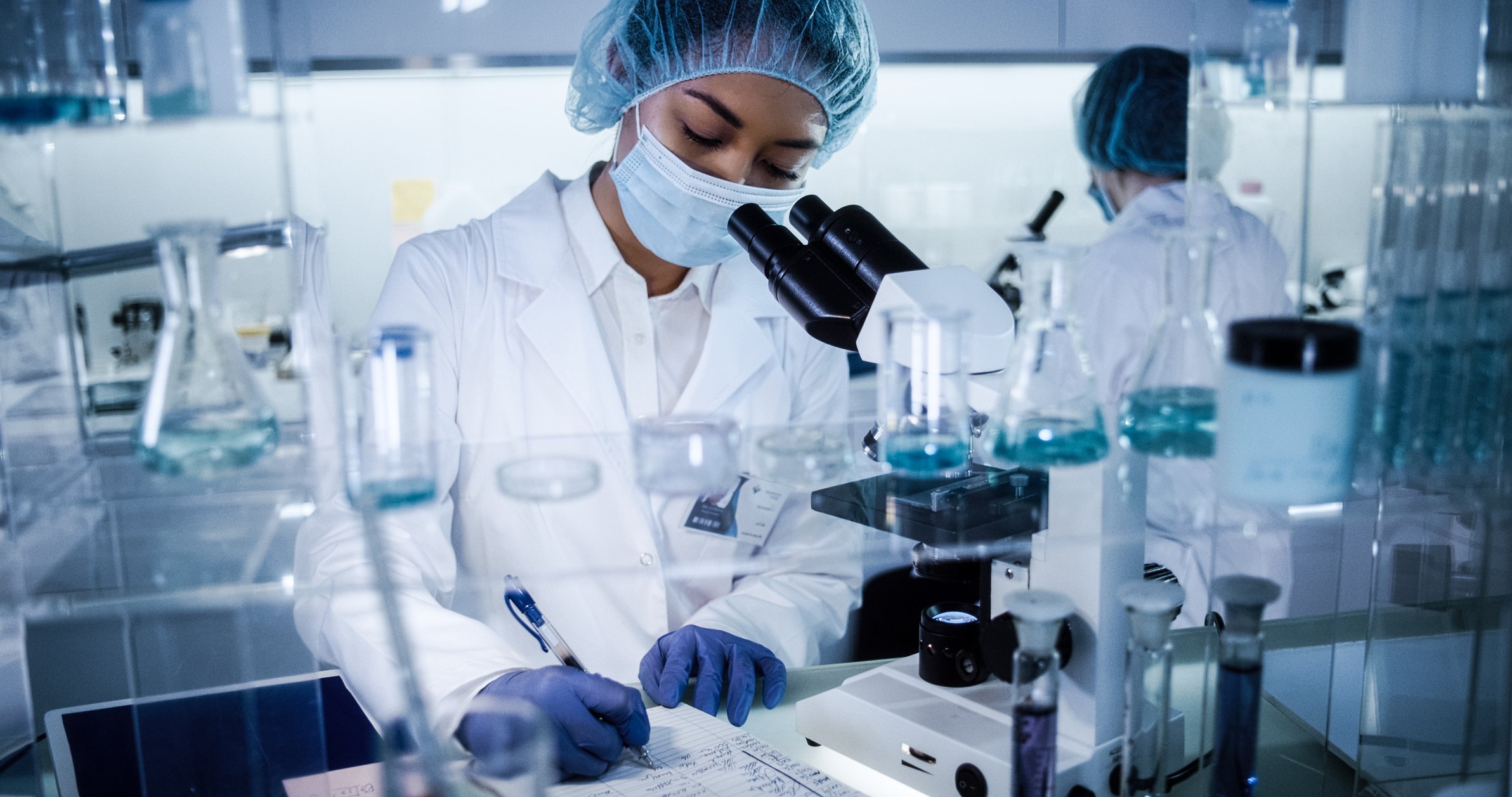 Researchers in protective equipment working in a pharmaceutical lab.