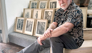 Artist Rob Clark sits with framed pages from his New Orleans sketchbook which will be on display in the exhibition "Extracting the Light" at the Beaumont Art League.