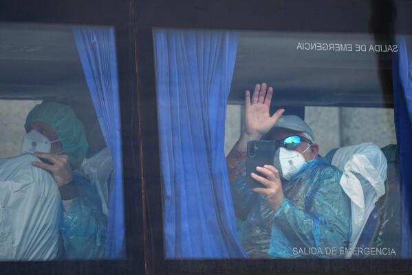 A passenger waves inside a bus after being disembarked from the hantavirus-stricken cruise ship MV Hondius at the port of Granadilla in Tenerife, Canary Islands, Spain, Sunday, May 10, 2026. (AP Photo/Manu Fernandez)