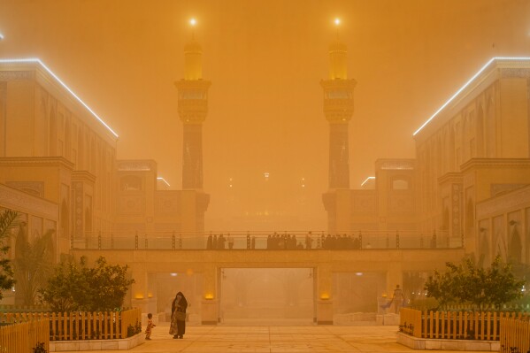 People walk near the Imam Ali shrine during a heavy dust storm in Najaf, Iraq, Monday, May 18, 2026. (AP Photo/Anmar Khalil)