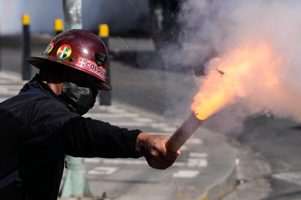 A miner launches a firecracker at police during an anti-government protest in La Paz, Bolivia, Monday, May 18, 2026. (AP Photo/Juan Karita)