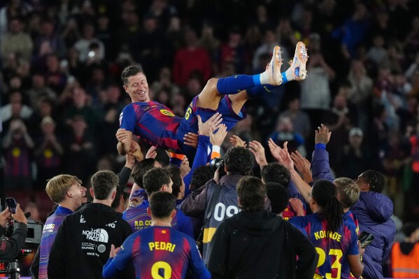Barcelona's Robert Lewandowski is thrown into the air by his teammates after his last game for the club at the end of the Spanish La Liga soccer match between FC Barcelona and Real Betis in Barcelona, Spain, Sunday, May 17, 2026. (AP Photo/Joan Mateu Parra)
