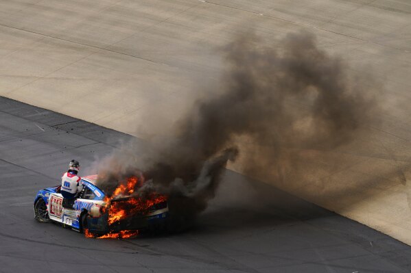 Ryan Preece climbs from his burning car after a crash during the NASCAR All-Star auto race at Dover Motor Speedway, Sunday, May 17, 2026, in Dover, Del. (AP Photo/Derik Hamilton)