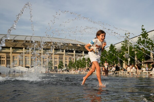A child cools herself off in a fountain in front of the Luzhniki stadium in Moscow, Monday, May 18, 2026, as the temperature reaches 30 degrees Celsius (86 degrees Fahrenheit). (AP Photo/Pavel Bednyakov)