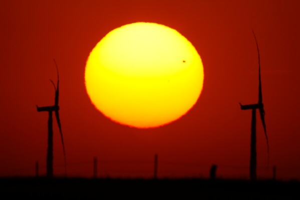 Wind turbines are silhouetted against the sky at sunset Friday, May 15, 2026, near Cimarron, Kan. (AP Photo/Charlie Riedel)