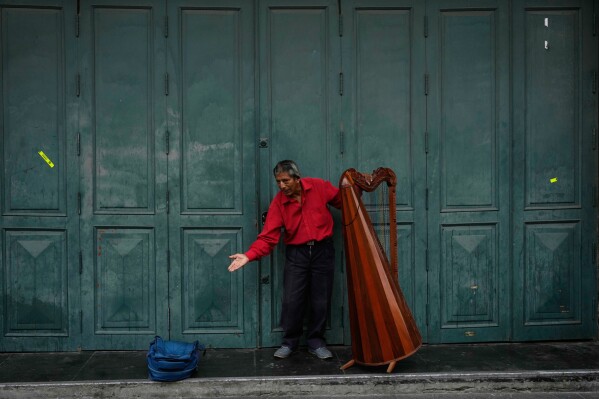A harp player bows after playing a song in downtown Lima, Peru, Tuesday, May 19, 2026. (AP Photo/Martin Mejia)