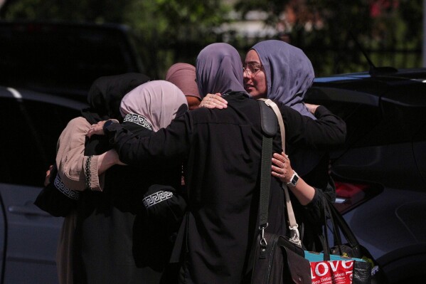 People embrace outside of the Islamic Center of San Diego, the day after a shooting, Tuesday, May 19, 2026, in San Diego. (AP Photo/Jae C. Hong)