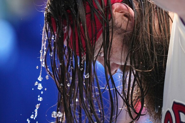 Philadelphia Phillies' Brandon Marsh pours water over his head to cool off during the fifth inning of a baseball game against the Cincinnati Reds, Wednesday, May 20, 2026, in Philadelphia. (AP Photo/Matt Rourke)