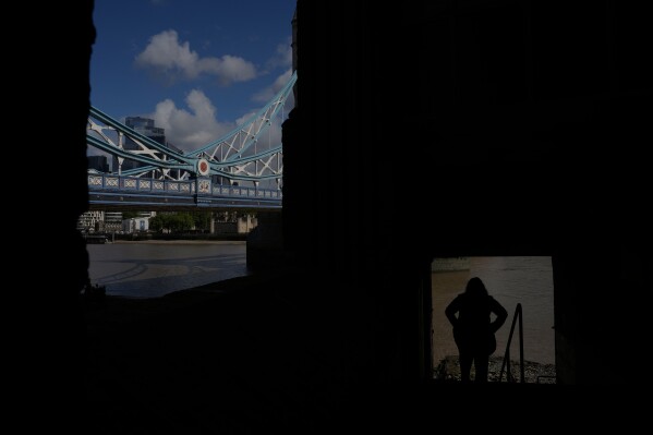 A woman stands next to Tower Bridge in London, Wednesday, May 20, 2026. (AP Photo/Kin Cheung)