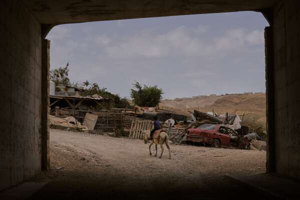 A Bedouin child rides a donkey in the hamlet of Khan al-Ahmar in the West Bank, Wednesday, May 20, 2026. (AP Photo/Mahmoud Illean)