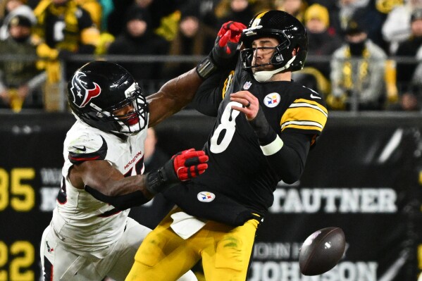 Pittsburgh Steelers quarterback Aaron Rodgers (8) loses possession of the ball while being tackled by Houston Texans defensive end Danielle Hunter (55) during the second half of an NFL wild-card playoff football game, Jan. 12, 2026, in Pittsburgh. (AP Photo/Justin Berl, File)