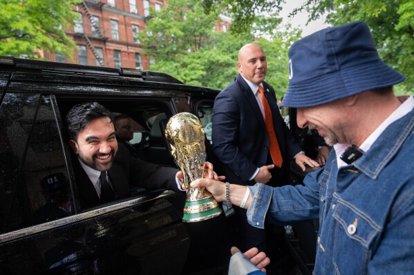 New York Mayor Zohran Mamdani is passed a replica World Cup Trophy by Ezequiel Cecchi, 49, after making a World Cup soccer tournament announcement at Harlem Tavern, Thursday, May 21, 2026 in New York. (AP Photo/Adam Gray)