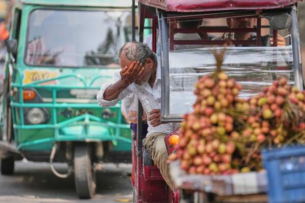An electric rickshaw driver splashes water on his face to cool off under the intense summer heat in Lucknow, India, Wednesday, May 20, 2026. (AP Photo/Rajesh Kumar Singh)