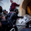 Trump supporters, including one holding a baseball bat and grabbing a police shield, clash with police and security forces outside a tunnel into the U.S. Capitol.