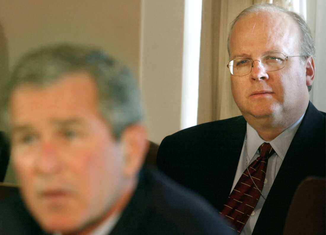 President George W. Bush (L) speaks to the news media as chief strategist, Karl Rove sits behind him, at the White House on Oct. 1, 2002. in Washington, D.C.