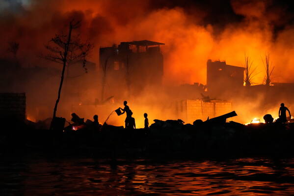 Residents uses buckets of water as they try to control the fire that hit a poor community in Manila, Philippines Saturday, May 23, 2026. (AP Photo/Aaron Favila)