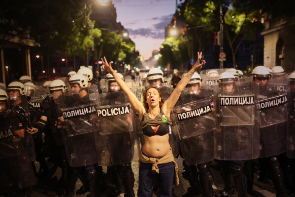 A woman who said she is pregnant stands in front of riot policemen as they prepare to disperse anti-government protesters during a rally led by Serbia's protesting university students who are pushing for major political changes in the Balkan country run by President Aleksandar Vucic, in Belgrade, Serbia, Saturday, May. 23, 2026. (AP Photo/Armin Durgut)